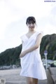 A woman in a white dress standing on a beach.