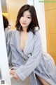 A woman in a bathrobe sitting in front of a mirror.