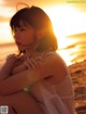 A woman sitting on the beach at sunset. 