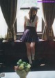 A woman sitting on a window sill in front of a window.