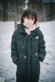 A woman standing in the snow wearing a black coat.