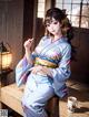 A woman in a kimono sitting at a table with a cup of tea.