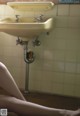 A woman sitting on the floor in front of a sink.