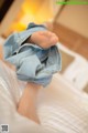 A doll's feet in a pair of jeans on a bed.