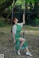 A woman in a green dress sitting on a swing.