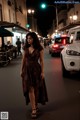 A woman walking down a city street at night.