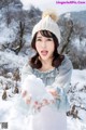 A woman in a white hat holding a snow ball.