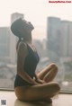 A woman in a black leotard sitting on a window sill.