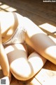 A woman in a white lingerie sitting on a wooden floor.