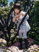 A woman in a white dress and black boots standing in a garden.