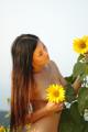 A naked woman standing in a field of sunflowers.